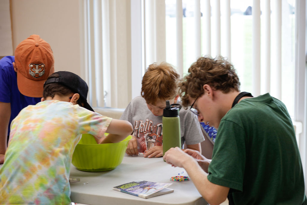 Children and a counsellor working together on a hands-on camp activity